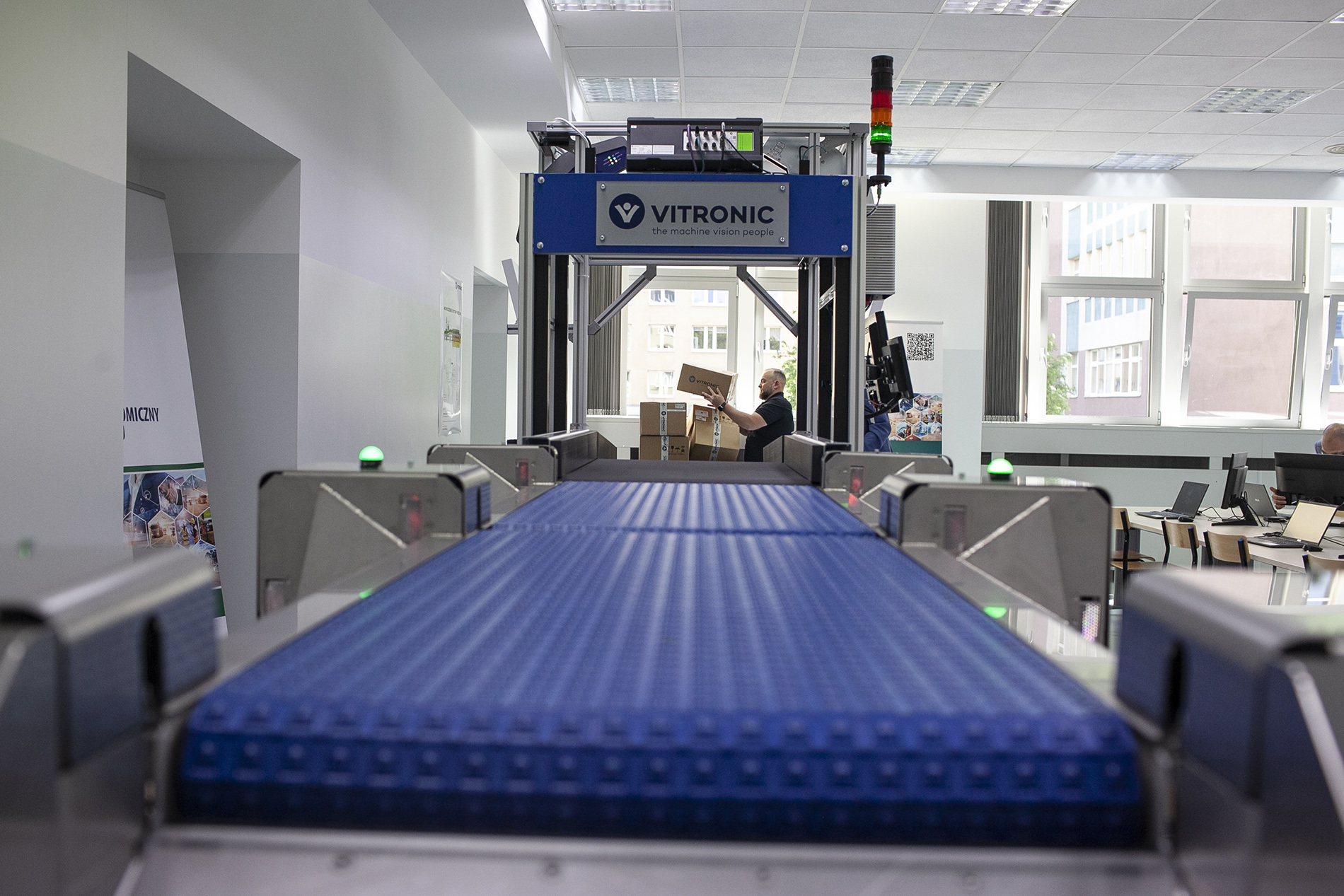 Umieszczanie kartonu na pasie sortowniczym w Laboratorium Automatyzacji Procesów Magazynowych na WIET na Politechnice Morskiej