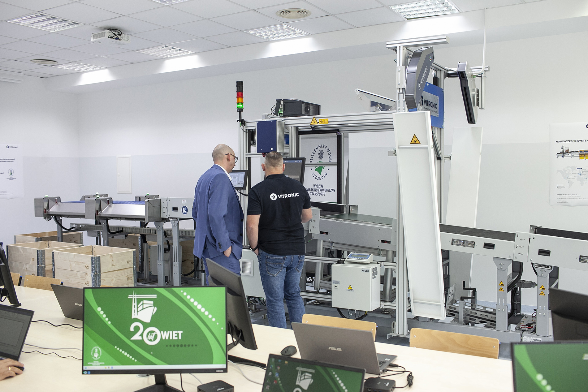 Dwoje pracowników przy pasie sortującym w Laboratorium Automatyzacji Procesów Magazynowych na WIET Politechniki Morskiej w Szczecinie